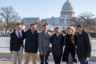 A group of students stand in front of the U.S. Capitol building in winter.